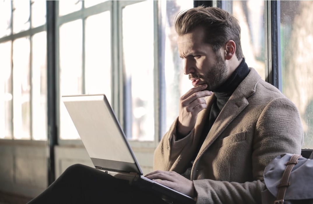 Man reading documents sent via digital fax services on a laptop.